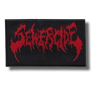 Puede incluir: Un parche rectangular negro bordado que presenta la palabra SEWERCIDE en una fuente roja estilizada y dentada. Las letras tienen un aspecto desgastado y goteante con bordes afilados, sobre un fondo de tela negra sólida con un borde visible.