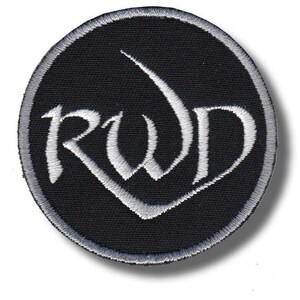 Op de afbeelding: Een ronde geborduurde patch met een zwarte achtergrond en een zilvergrijze rand. De letters RWD zijn in een gestileerd, zilvergrijs lettertype in het midden geborduurd, waarbij de onderkant van de W uitloopt in een puntige vorm.
