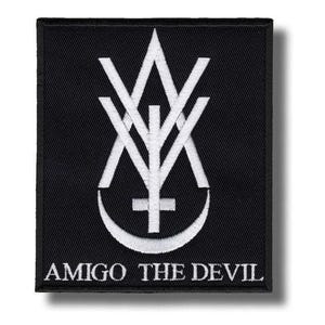 May include: A rectangular black embroidered patch featuring a white stitched logo consisting of a stylized letter A and Y intertwined with a cross and a crescent moon shape. The text AMIGO THE DEVIL is embroidered in white at the bottom edge.