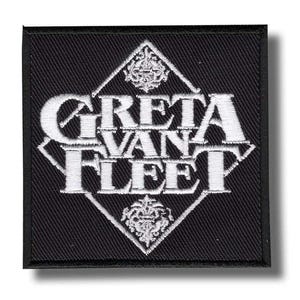 May include: A square black embroidered patch featuring the white text GRETA VAN FLEET centred within a white diamond outline. Above and below the text are intricate white decorative filigree ornaments, all set against a black fabric background.
