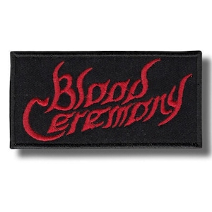 Op de afbeelding: Een rechthoekige geborduurde patch met een zwarte achtergrond en rood stiksel. De tekst Blood Ceremony is in het midden van de patch geborduurd in een gestileerd, gotisch lettertype, afgewerkt met een dikke zwarte rand rondom.