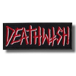 Peut inclure: Un écusson rectangulaire brodé sur fond noir avec le mot DEATHWISH cousu en lettres capitales rouge vif. Le lettrage présente un aspect légèrement usé et dessiné à la main, avec une bordure noire épaisse tout autour du contour.