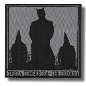 Op de afbeelding: Een vierkante geborduurde patch met een zwart silhouet van drie figuren tegen een grijze achtergrond. De centrale figuur is groter met puntige oren, geflankeerd door twee kleinere figuren met puntige kappen. De tekst TERRA TENEBROSA - THE PURGING staat onderaan.