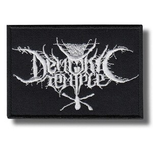May include: A rectangular black embroidered patch featuring white thread stitching. The design displays the text Demonic Temple in a stylized, jagged, and thorny font, with a central vertical symbol resembling a cross or an inverted dagger.