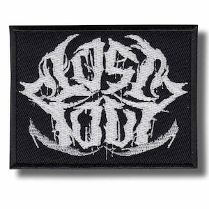 May include: A rectangular black fabric patch featuring white embroidered text that reads "LOST SOUL" in a stylised, jagged, and distressed font. The embroidery has a dense, textured appearance with a thick black border surrounding the design.
