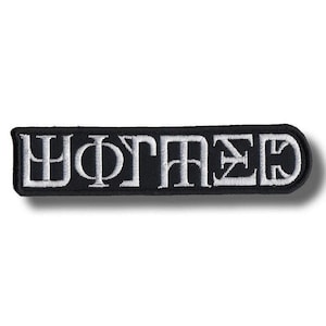 May include: A rectangular black embroidered patch with rounded corners featuring white stitched lettering that reads "WOTMED" in a stylised, blocky font. The embroidery has a raised texture and a clean, defined border against the black fabric background.