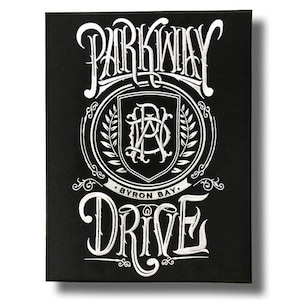 May include: A rectangular black fabric patch featuring white embroidered text and graphics. The design displays the words Parkway Drive in a stylized font, with a central shield emblem containing the letters PWD and the text Byron Bay below.