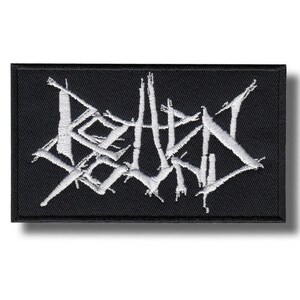 Pode incluir: Um emblema retangular bordado em preto com fios brancos que formam o texto estilizado Rotten Sound. As letras apresentam uma fonte serrilhada, afiada e angular, cercadas por uma borda preta espessa que contorna todo o design da peça.