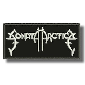 Puede incluir: Un parche rectangular bordado en negro que presenta el texto blanco Sonata Arctica en una fuente estilizada de bordes afilados. El diseño está centrado sobre un fondo de tela negra con un borde negro grueso y cosido que rodea la forma.