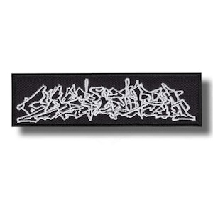 Puede incluir: Un parche rectangular negro bordado con hilo blanco en una fuente compleja, estilizada e ilegible de estilo grafiti. El diseño está centrado sobre la tela, que presenta una textura tejida visible y bordes limpios y rectos.