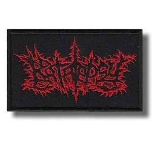 May include: A rectangular black embroidered patch featuring a stylized, jagged red text design in a death metal font style. The embroidery is dense, with sharp, pointed edges forming the lettering against the solid black fabric background.