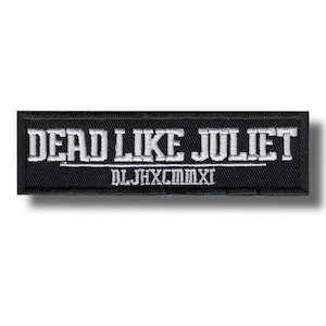 May include: A rectangular black embroidered patch featuring the white text DEAD LIKE JULIET in a bold serif font. Below the text is a thin horizontal line and the Roman numerals DLJHXCMMXI embroidered in white thread on a black background.