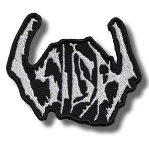 Pode incluir: Um emblema bordado em preto e branco com uma fonte estilizada e irregular que diz "SISH". O design tem uma estética afiada e agressiva com extensões pontiagudas em forma de chifres nos lados esquerdo e direito, com uma borda preta espessa.