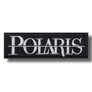 Op de afbeelding: Een rechthoekige zwarte geborduurde patch met het woord POLARIS in witte hoofdletters. Een dunne witte horizontale lijn loopt door het midden van de tekst en verdeelt de letters. De patch heeft een zwarte geborduurde rand.