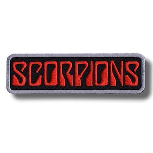 Pode incluir: Um emblema retangular bordado com a palavra SCORPIONS em letras maiúsculas vermelhas em negrito. O texto está sobre um fundo preto sólido e todo o emblema é emoldurado por uma borda fina costurada na cor cinza claro.