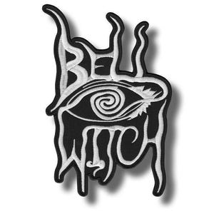 May include: A black and white embroidered patch featuring the text Bell Witch in a stylized, flowing font. The design incorporates a central eye graphic with a spiral pupil, surrounded by elongated, dripping, and vine-like white embroidery.