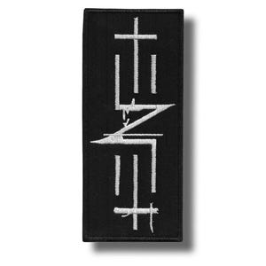May include: A rectangular black embroidered patch featuring the white text TENET arranged in a stylised, vertical, and mirrored design. The letters are stitched with clean white thread against a solid black fabric background with a stitched border.