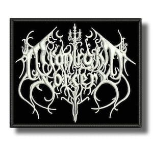 May include: A rectangular black fabric patch featuring white embroidered text that reads "Moonbound Sorcery" in a stylized, intricate, and jagged font. The design includes symmetrical, vine-like flourishes and a central candelabra motif.