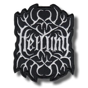 以下が含まれることがあります： 黒い刺繍ワッペン。白い糸で複雑で左右対称の枝のような模様が描かれ、中央の様式化された判読不能な白い文字と一体化している。全体はギザギザとした不規則な縁取りで囲まれている。