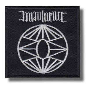 May include: A square black embroidered patch featuring white thread detailing. The top portion displays the word "Imminence" in a stylized gothic font. Below the text is a circular geometric design composed of radiating lines and a central oval.
