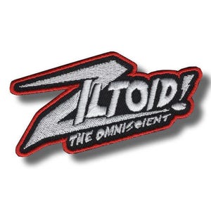 May include: An embroidered patch featuring the text ZILTOID! in white with a black background and a red border. Below the main text, the words THE OMNISCIENT are embroidered in white. The design has a sharp, angular shape with a stylised letter Z.