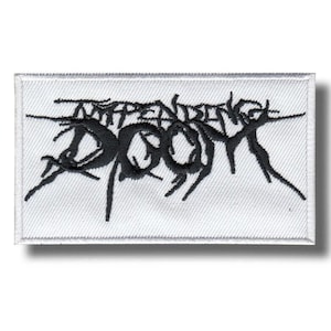 May include: A rectangular embroidered patch with a white background and a black stitched design. The text reads Impending Doom in a stylised, jagged, and sharp font that spans the width of the patch with thin, pointed lines extending outwards.