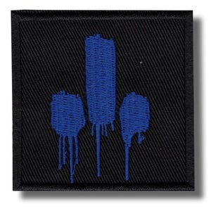May include: A square black embroidered patch featuring three vertical blue shapes that resemble paint drips. The central shape is the tallest, flanked by two shorter shapes on either side, all rendered in a textured blue thread on a black background.