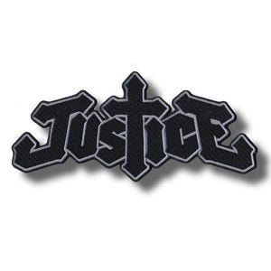 Puede incluir: Un parche bordado negro que muestra la palabra Justice en una fuente gótica estilizada. La letra t está diseñada como una cruz y todo el texto está delineado con un borde gris claro, creando un contraste nítido sobre el fondo de tela negra.