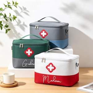 Puede incluir: Tres bolsas de almacenamiento médico rectangulares con asas superiores y cierres de cremallera. Cada bolsa presenta un emblema de cruz roja y blanca en el frente. Las bolsas son de color gris y azul, verde oscuro y gris, y blanco y rojo con nombres.