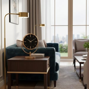 Puede incluir: Un reloj de mesa redondo con esfera de madera negra y manecillas doradas, montado sobre un marco y base circular de metal dorado. El reloj presenta finas marcas de hora doradas y está colocado sobre una mesa auxiliar de madera marrón oscura.