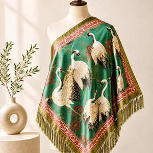 Peut inclure: Un foulard carré vert émeraude orné d'un motif répétitif de grues blanches à couronne rouge, agrémenté de motifs floraux rouges. Le foulard est bordé d'une garniture décorative rouge et dorée et fini avec de longues franges vertes assorties.