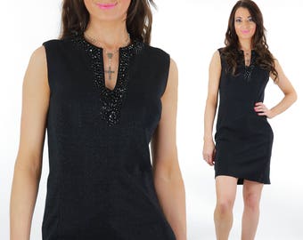 May include: A black sleeveless dress with a beaded neckline. The dress is fitted and has a straight hemline.