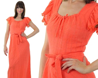 Könnte beinhalten: Ein langes, korallenfarbenes Maxikleid mit quadratischem Ausschnitt, kurzen Ärmeln mit Spitzenbesatz und einem Bindegürtel in der Taille.