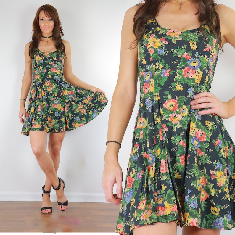 May include: A dark green sleeveless dress with a floral print in shades of yellow, pink, and blue. The dress has a fitted bodice and a flared skirt.