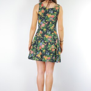 May include: A sleeveless black dress with a floral print featuring pink, yellow, and blue flowers. The dress has a fitted bodice and a flared skirt.