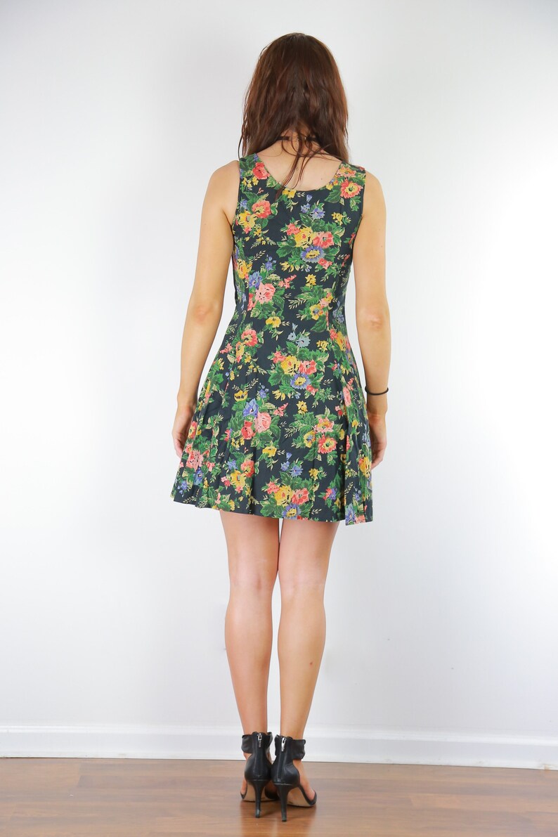 May include: A sleeveless black dress with a floral print featuring pink, yellow, and blue flowers. The dress has a fitted bodice and a flared skirt.