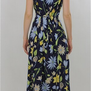 Pode incluir: Um vestido midi azul marinho com estampa floral com flores amarelas, azuis e verdes. O vestido tem um la&ccedil;o na cintura e &eacute; sem mangas.