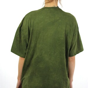 May include: A green t-shirt with a faded, tie-dye pattern. The shirt has a crew neck and short sleeves.