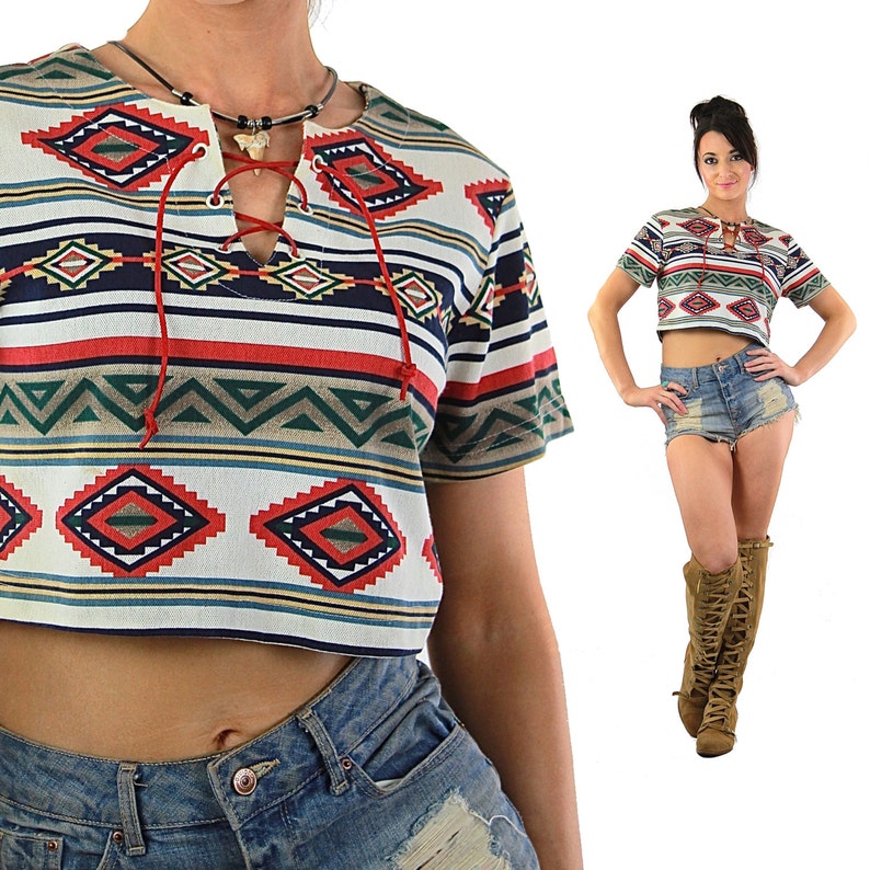 May include: A white, red, blue, and green cropped t-shirt with a geometric pattern. The shirt has a lace-up neckline and short sleeves.