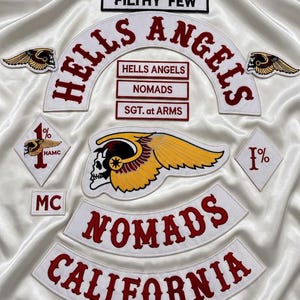 May include: A collection of embroidered patches featuring the text HELLS ANGELS, NOMADS, CALIFORNIA, FILTHY FEW, MC, and SGT. at ARMS. The set includes a large winged skull emblem, two smaller winged skull patches, and two diamond-shaped 1% patches.