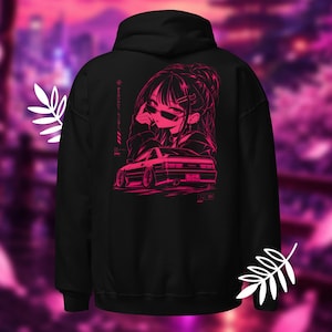 May include: A black hoodie featuring a vibrant pink graphic on the back. The design displays an anime-style character wearing sunglasses positioned above a sports car. Japanese text is printed vertically next to the character's head.