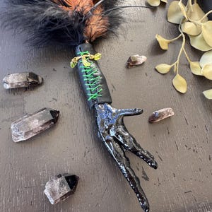 Smudge wand with black chicken foot, green stones, and black/brownfeathers