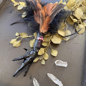 Smudge wand with black chicken foot, pink stones, and feathers