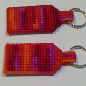 May include: Two colorful keychains with a red, orange, and pink striped pattern. Each keychain has a silver metal ring.