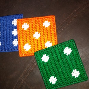 May include: Three crocheted squares with white polka dots. The squares are blue, orange, and green.