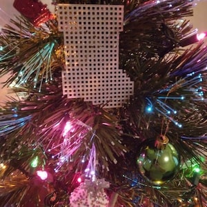 May include: A Christmas tree decorated with colorful lights, a white plastic stocking, and a green glass ornament.