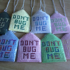May include: Eight crocheted house-shaped ornaments with the text "Don't Bug Me" in various colors, including green, yellow, blue, pink, and white.