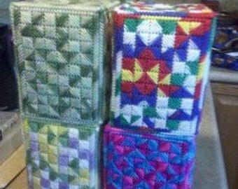 Könnte beinhalten: Vier handgefertigte Taschentuchbox-Bezüge mit bunten geometrischen Mustern. Die Bezüge sind aus Plastik-Canvas gefertigt und in verschiedenen Farben gehalten, darunter Grün, Gelb, Blau, Rot und Lila.