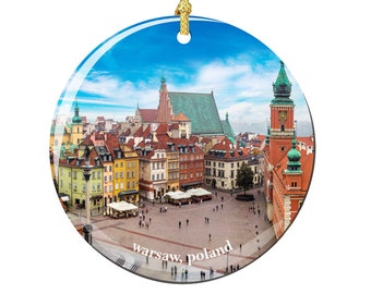 May include: A round glass bauble featuring a colourful cityscape with a blue sky and white clouds. The city is dominated by a tall, red building with a green roof and a clock tower. The text "warsaw, poland" is printed in white at the bottom of the bauble.