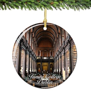 May include: A round glass bauble featuring a photograph of the interior of the library at Trinity College Dublin. The photo shows tall bookshelves filled with books, a high vaulted ceiling, and a long hallway.
